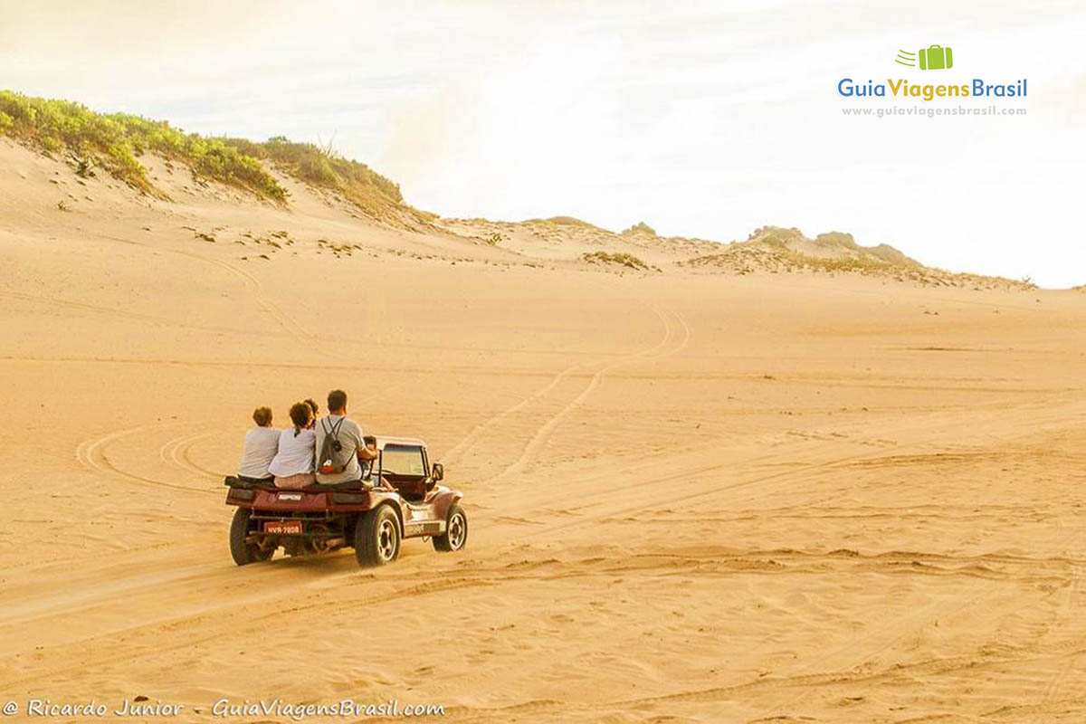 Imagem de turistas passeando de bugue pelas dunas.